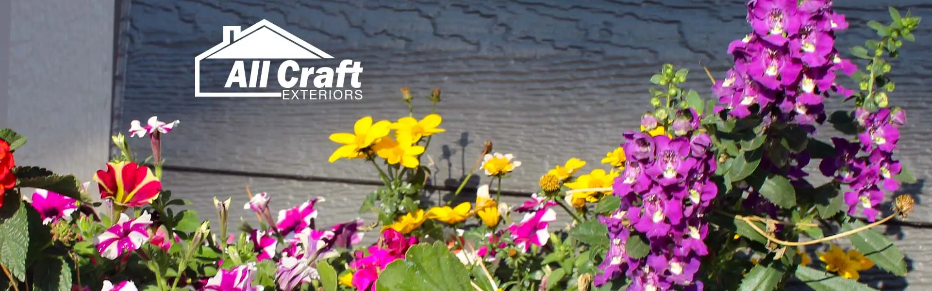 Close-up of LP SmartSide textured siding with a flowerbed in front, featuring colorful flowers and detailed lap siding grain.
