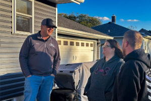 All Craft Exteriors customer review photo featuring Corey Keane with homeowners Lisa and Scott Osland at their renovated home in Grand Meadow, Minnesota.