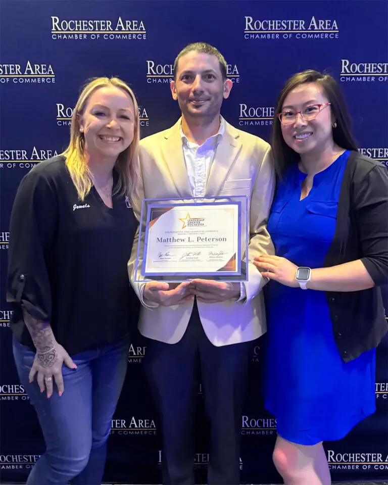 Jewels DeCorsey, Matt Peterson, and Xee Xiong pose together as Matt holds his Greater Leadership Rochester diploma at the graduation ceremony.
