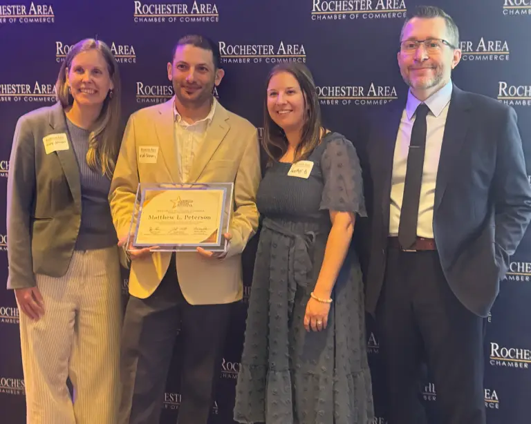 Matt Peterson poses with Greater Leadership Rochester attendees while holding his graduation certificate.