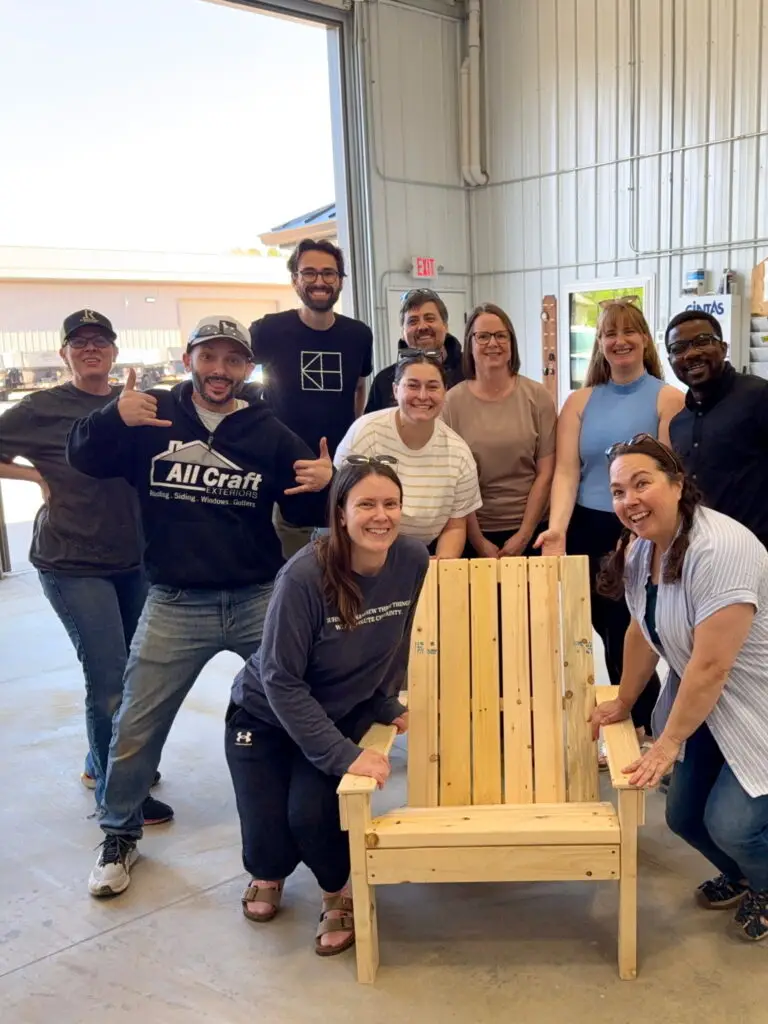 Matt Peterson and fellow Greater Leadership Rochester participants pose around a handcrafted chair created for the “Tools for Tomorrow” community project.